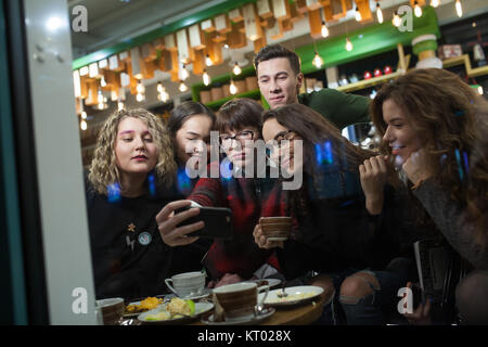 Grupo de adolescentes positivo hacer selfies y pasar tiempo en un café. Foto de stock