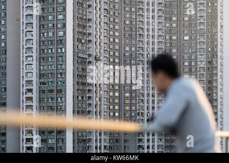 Retrato de un hombre asiático enfrente de un gran bloque de apartamentos en Hong Kong.