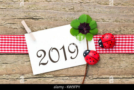 Tarjeta de Año Nuevo 2019 con hojeados trébol y mariquitas sobre fondo de madera Foto de stock