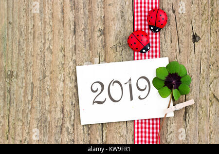 Tarjeta de Año Nuevo 2019 con hojeados trébol y mariquitas sobre fondo de madera Foto de stock