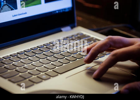 Joven utiliza el portátil para pagar sus facturas electrónicamente con su tarjeta de crédito Foto de stock
