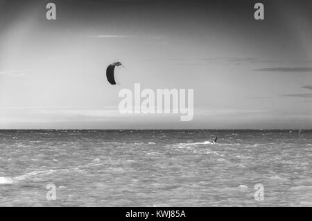 Puesta de sol en blanco y negro con kite surf disfrutando del mar al atardecer Foto de stock