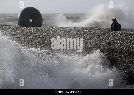 Un par permanezca cerca de la 'a flote' escultura de East Sussex escultor Hamish negro, mientras las olas rompen en la playa en Brighton, Sussex, como un nuevo aviso de vientos fuertes ha sido emitido para la mayor parte de Inglaterra y Gales el jueves. Foto de stock