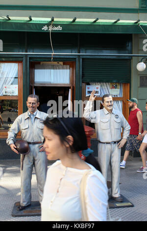 Los turistas cruzar delante de estatuas de piloto de carreras Oscar Gálvez fuera La Biela cafe, Recoleta, Buenos Aires, Argentina