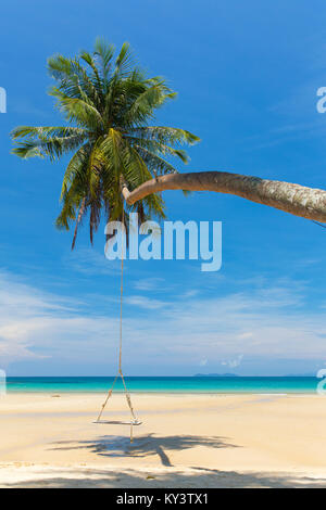 Columpio de madera colgando sobre la playa en una isla tropical.