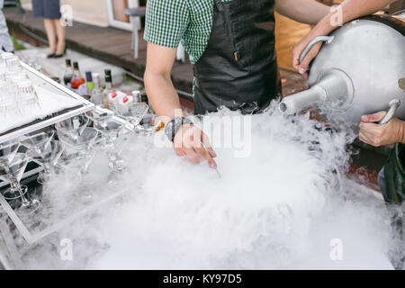 Los barman servir el cóctel en un recipiente grande con nitrógeno líquido. Línea de fila de diferentes bebidas cócteles en una fiesta de cumpleaños o el día de la boda.