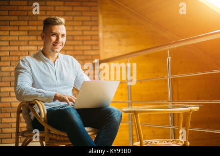 Hombre sentado en el hogar y el trabajo en equipo portátil de trabajo masculino de loft home office Foto de stock