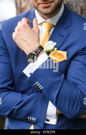 El novio en traje azul, reloj y arreglo floral para la solapa del novio. Foto de stock