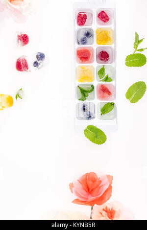 Vista superior de bayas y frutas en cubitos de hielo con flores aisladas blanco ob Foto de stock