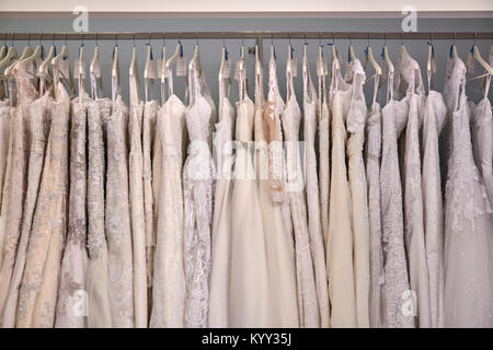 vestidos de novia colgando en el estante de la ropa en la tienda Foto de stock