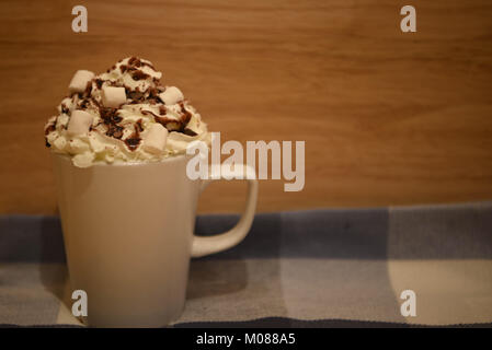 Comida y bebida imagen fotografía de una fresca bebida de chocolate caliente en una taza o vaso blanco coronado con crema batida mini malvaviscos y chocolate
