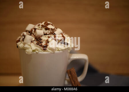 Comida y bebida imagen fotografía de una fresca bebida de chocolate caliente en una taza o vaso blanco coronado con crema batida mini malvaviscos y chocolate