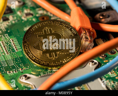 Moneda Bitcoin pararse en la placa base del ordenador Foto de stock