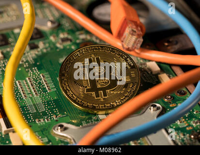 Moneda Bitcoin pararse en la placa base del ordenador Foto de stock