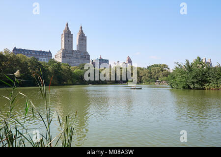 Estanque Central Park en Nueva York con el barco y el edificio San Remo, cielo azul en un día soleado