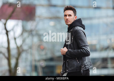 Moda de invierno hipster. traje de invierno cómodo. ropa de hombre con  estilo de invierno. hombre de pie cálida chaqueta negra y rosa con capucha  en la valla