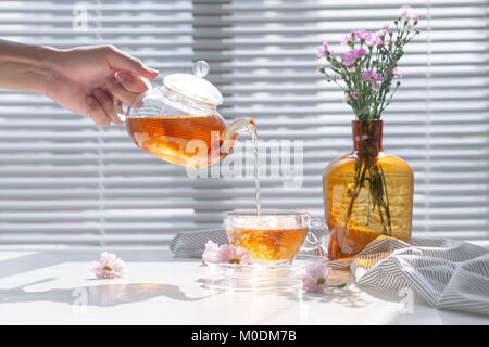 Se vierte el té en vaso de vidrio en la mañana. Foto de stock