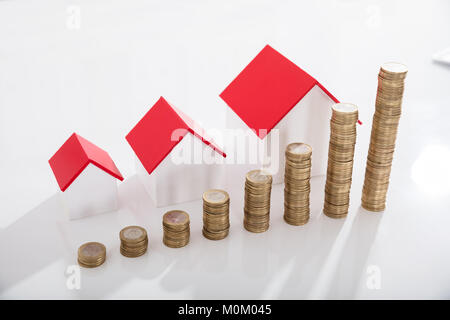 Vista elevada de modelos de la casa y pila de monedas en el mostrador blanco