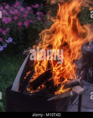 Fuego brillante en parrilla al atardecer jardín de verano Foto de stock