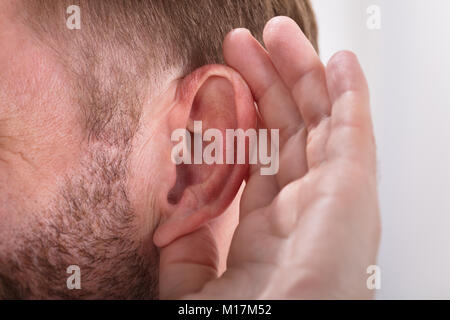 Close-up de un hombre que intenta oír con entregar la oreja Foto de stock