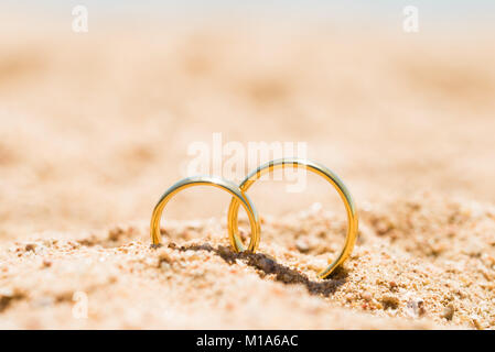 Dos anillos de oro en la arena en la playa Foto de stock