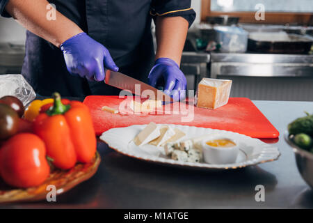 Corte al hombre con uniforme y guantes usando un cuchillo para cortar dulce  pastel fresco en la mesa en la panadería Fotografía de stock - Alamy