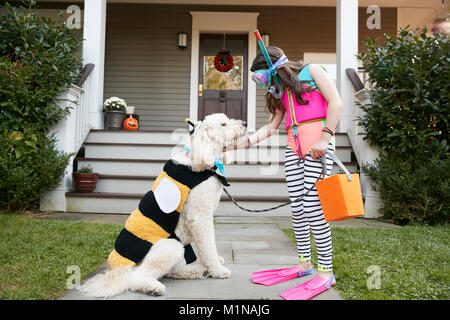 Chica con perro vistiendo disfraces para Halloween truco o tratar Foto de stock