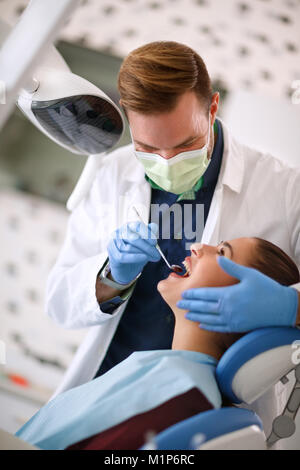 Dentista verificando los dientes de la mujer en clínica dental Foto de stock