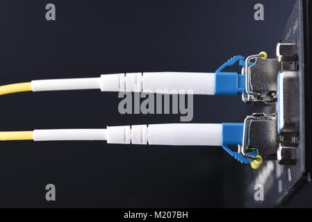 Tecnología de dispositivos de red de fibra óptica, cable e interruptor de cierre sobre fondo negro Foto de stock