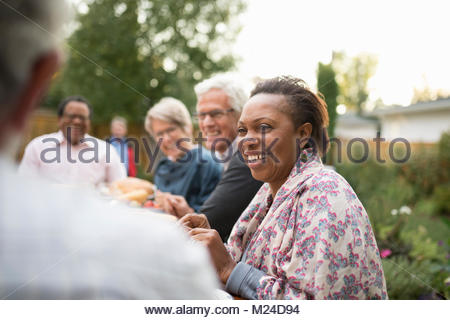 Sonriente mujer senior disfrutando garden party almuerzo con amigos en el patio