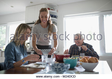 Hijas sonriente y altos padre comiendo en la mesa de la cocina