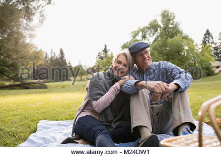 Retrato sonriente, cariñoso altos par disfrutar de un picnic en el parque