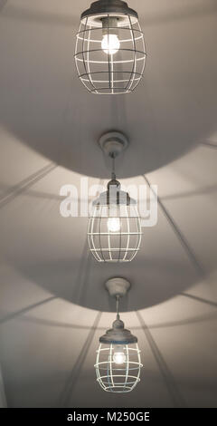 Tres iluminados y colgar lámparas blancas en fondo blanco. Foto de stock