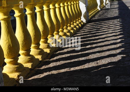 Postes de hormigón amarillo proyecte sombras sobre un puente en la brillante luz del sol