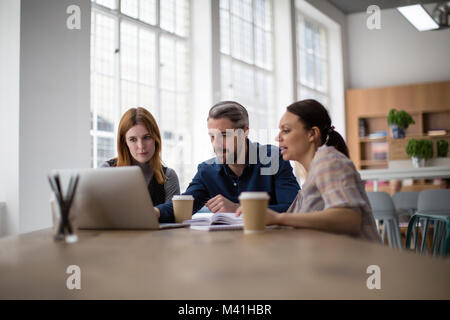Compañeros mirando un portátil en una reunión