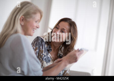 Amigos en busca de hembras maduras en una tableta digital Foto de stock