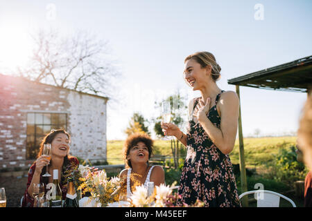 Abrumada mujer compartir buenas noticias con amigos en el restaurante del jardín. Amigos celebrando una ocasión especial en la fiesta de verano al aire libre.