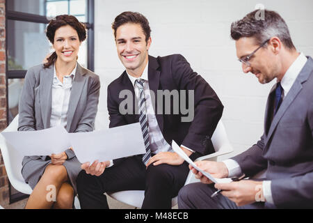 Los profesionales empresariales alegre celebración documentos mientras estaba sentado en el sofá Foto de stock