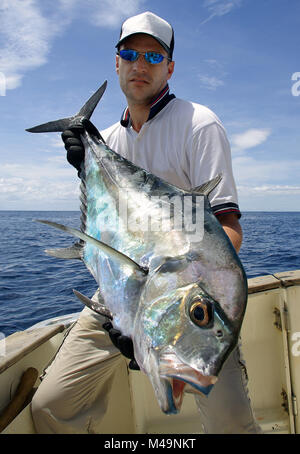 Pesca en mar profundo - Feliz pescador sosteniendo un trevally jack Foto de stock