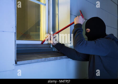 Ladrón con antifaz negro con una palanqueta para irrumpir en una casa por  la noche Fotografía de stock - Alamy