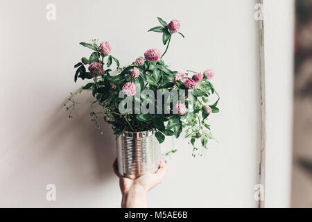 Mano sujetando el trébol bouquet con flores rosas en caña metálico. flores  silvestres en rústica casa rural país vida lenta Fotografía de stock - Alamy