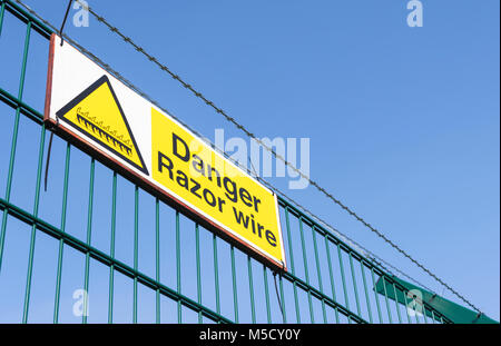 Peligro de una alambrada señal de advertencia en la parte superior de una valla de seguridad en el Reino Unido. Foto de stock