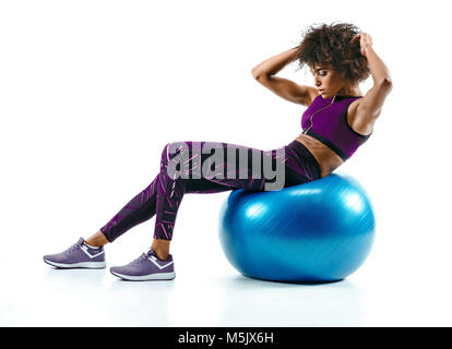 Mujer joven haciendo ejercicio abs en fitness ball. Foto de la muchacha africana en silueta sobre fondo blanco. Concepto de Fitness y estilo de vida saludable Foto de stock