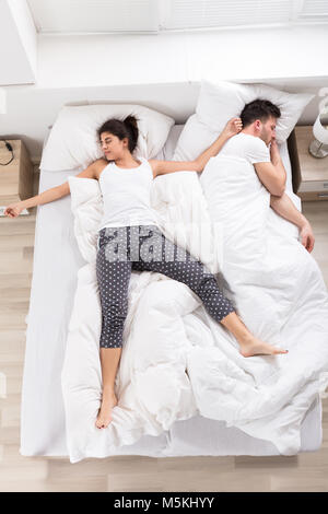 Vista aérea de la joven mujer durmiendo junto a su marido en la cama