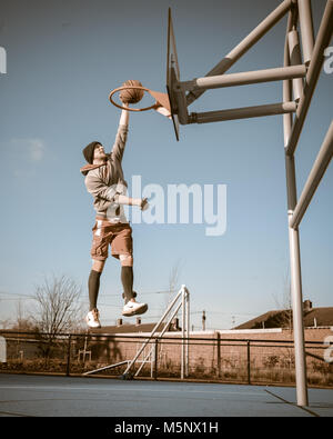 Un rodaje en exteriores de un jugador de baloncesto en Devizes, Wiltshire. Rodada en la luz solar natural en una cancha de baloncesto. Amplia profundidad de archivado, con buena iluminación.