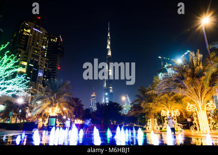 Dubai, Emiratos Árabes Unidos - Octubre 18, 2017: Dubai escena nocturna con mega altos rascacielos Burj Khalifa ver y colorida fuente decorativa Foto de stock