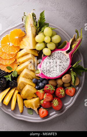 Plato de frutas exóticas con uva, fruta del dragón, longan y piña Foto de stock