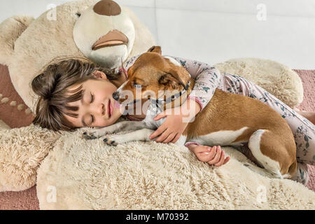 Niña de seis años siendo besado por su perro en un oso gigante Foto de stock