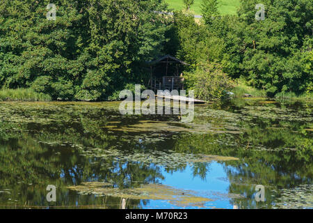 Cabaña de madera reflejando en un lago en la ruta romántica en Alemania Foto de stock