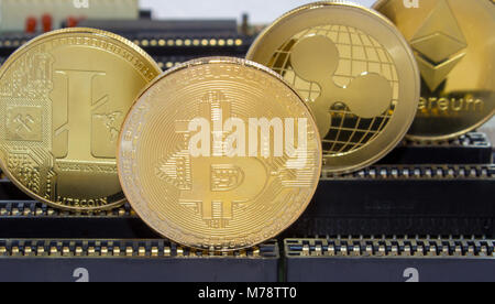 En una placa base de las ranuras son monedas de oro permanente de monedas - criptografía digital bitcoin litecoin rizado. Foto de stock